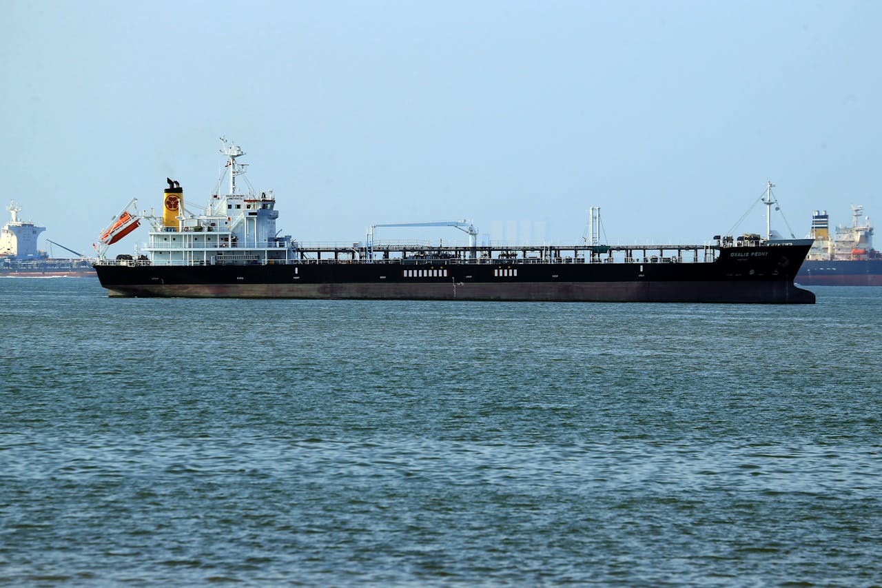 Services Oil tanker navigating calm ocean waters near a coastal harbor. Clear day view.