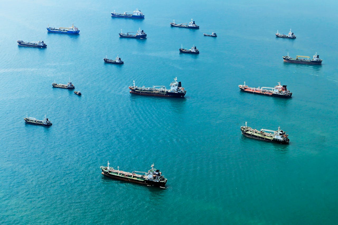 Services Numerous cargo ships anchored on the blue ocean, captured from above.