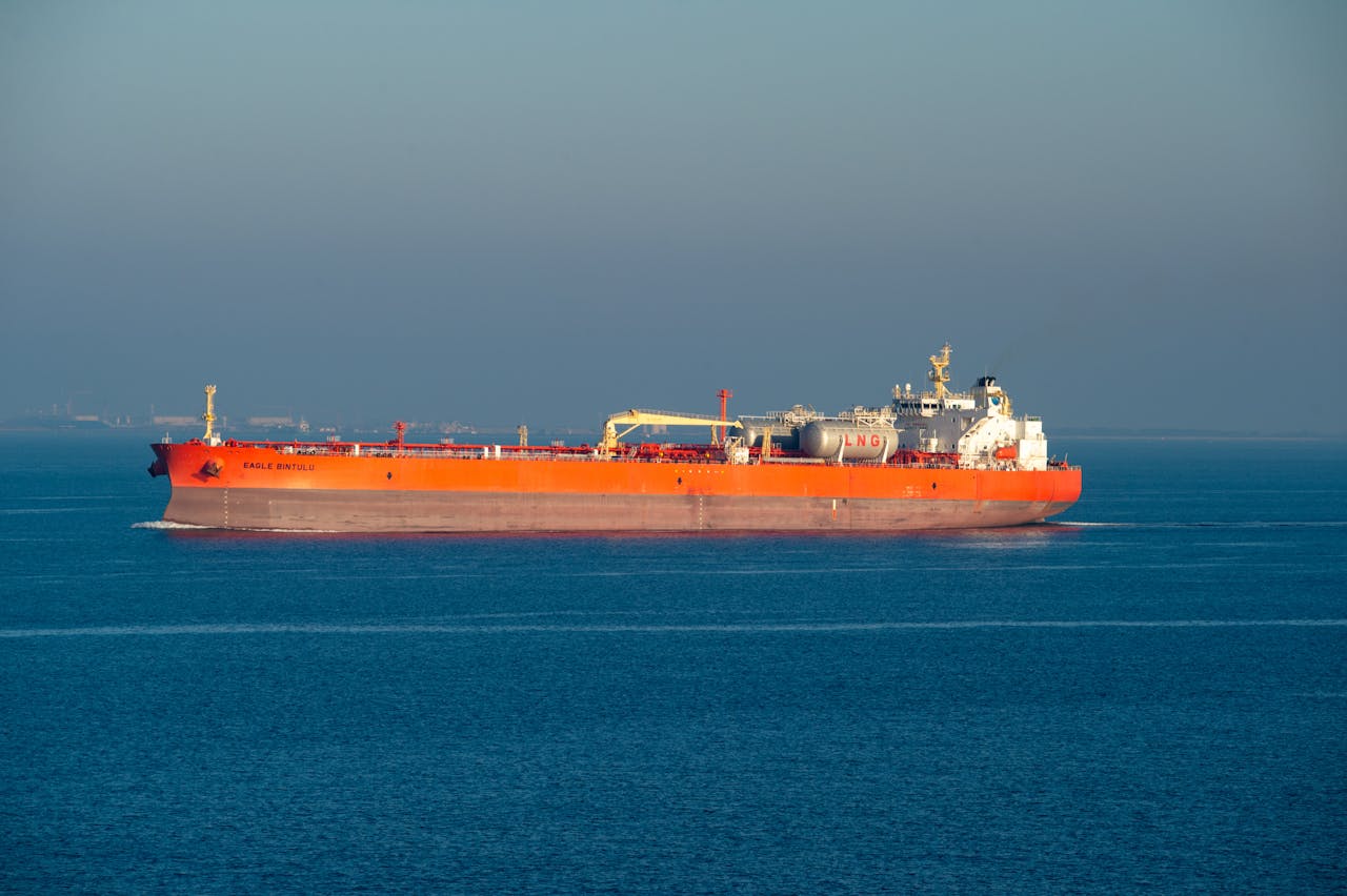 Services Bright orange LNG carrier ship cruising through calm sea waters on a clear day.